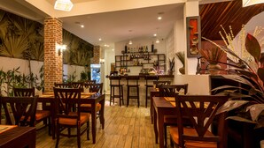 A restaurant with wooden flooring, brick pillar, and various plants. - VMANSION Boutique Hotel (Phnom Penh)