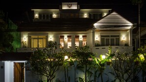 A modern two-story house with a balcony, illuminated exterior lights, and a gated entrance. - VMANSION Boutique Hotel (Phnom Penh)