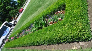 A landscaped garden with a lawn, flower beds, and a parked vehicle. - Star Inn by Elevate Rooms (Niagara Falls)