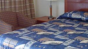 A hotel room with a bed, a chair, a nightstand, a lamp, and a window with curtains. - Star Inn by Elevate Rooms (Niagara Falls)