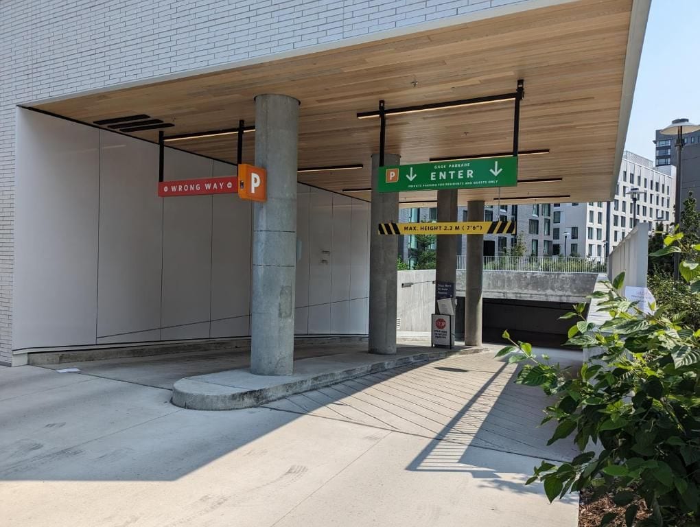 Entrada de estacionamiento con un letrero que indica una altura máxima de 2,3 metros.