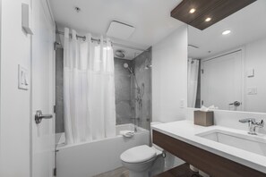 Un baño moderno con ducha envuelta en vidrio, inodoro blanco y tocador con espejo.