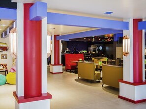 Un interior moderno con una zona de bar, asientos y una cocina al fondo.