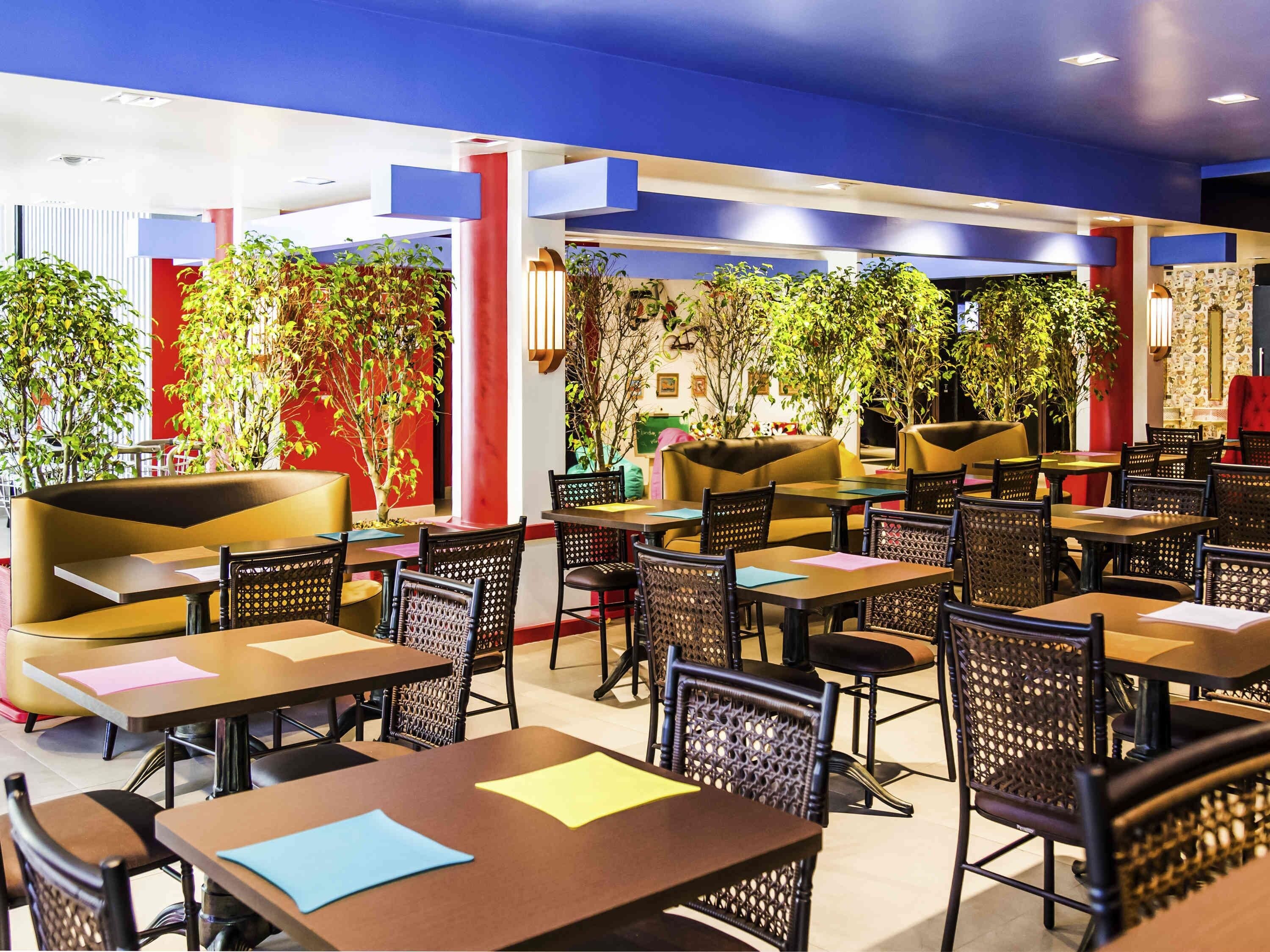 A restaurant with indoor seating, tables, chairs, and potted plants.