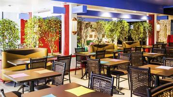 A restaurant with indoor seating, tables, chairs, and potted plants.