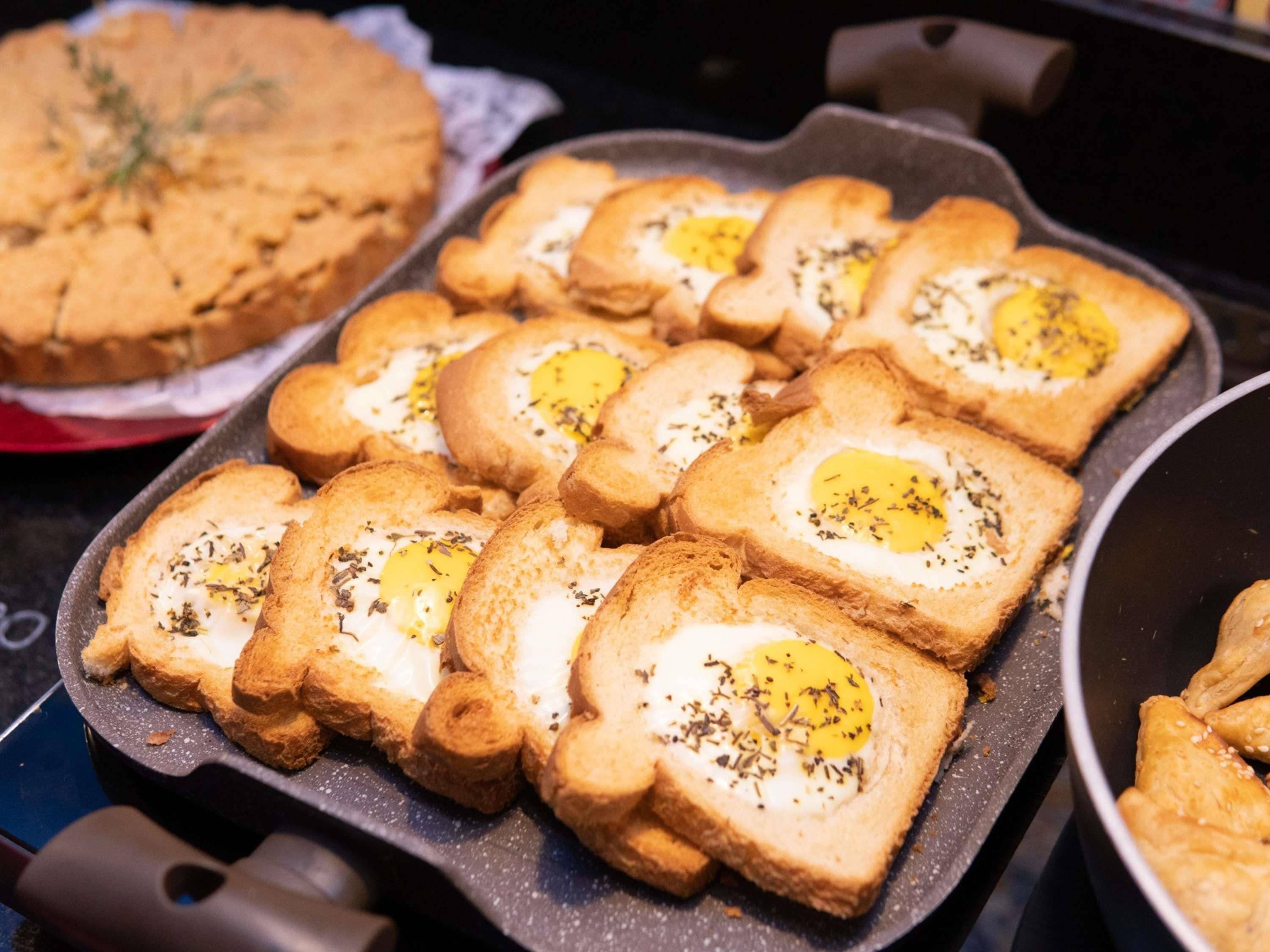 A pan with toasted bread slices topped with eggs and herbs.