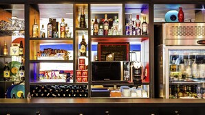A bar area with shelves of liquor bottles, a coffee machine, and a refrigerator.