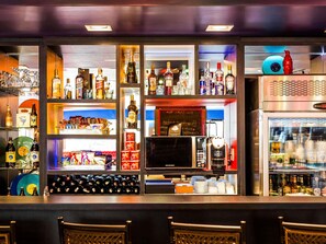 A bar area with shelves of liquor bottles, a coffee machine, and a refrigerator. - ibis Styles Porto Alegre Centro (Porto Alegre)