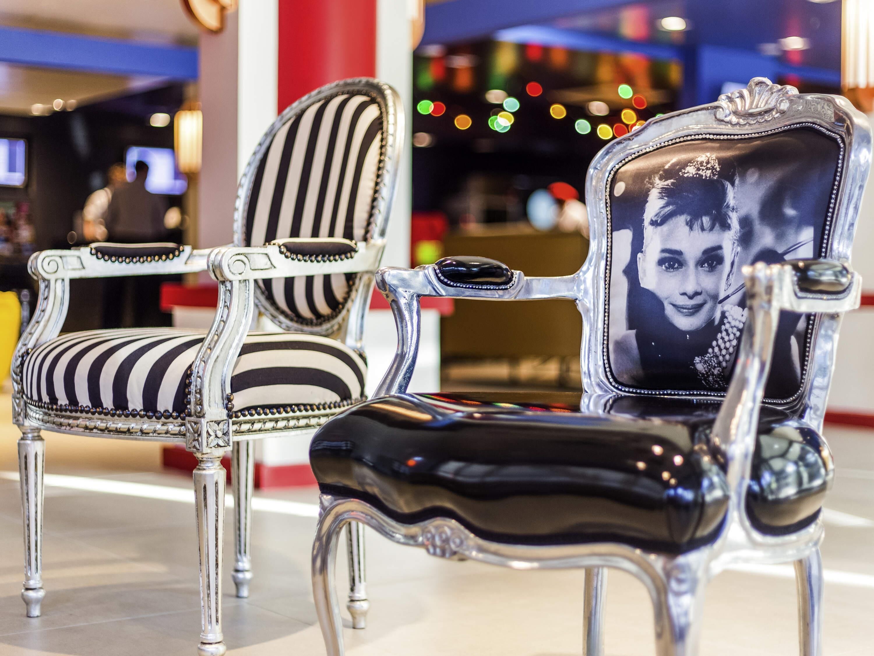Two ornate chairs with black and white striped upholstery and silver metal frames.