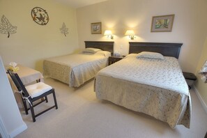 Habitación de hotel con dos camas, un escritorio y una silla.