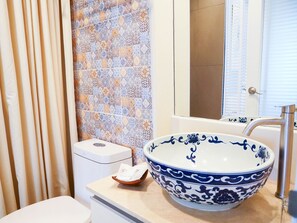 A bathroom with a large blue and white bowl sink, a toilet, and a tiled backsplash. - O'nya Phuket Hotel (Wichit)