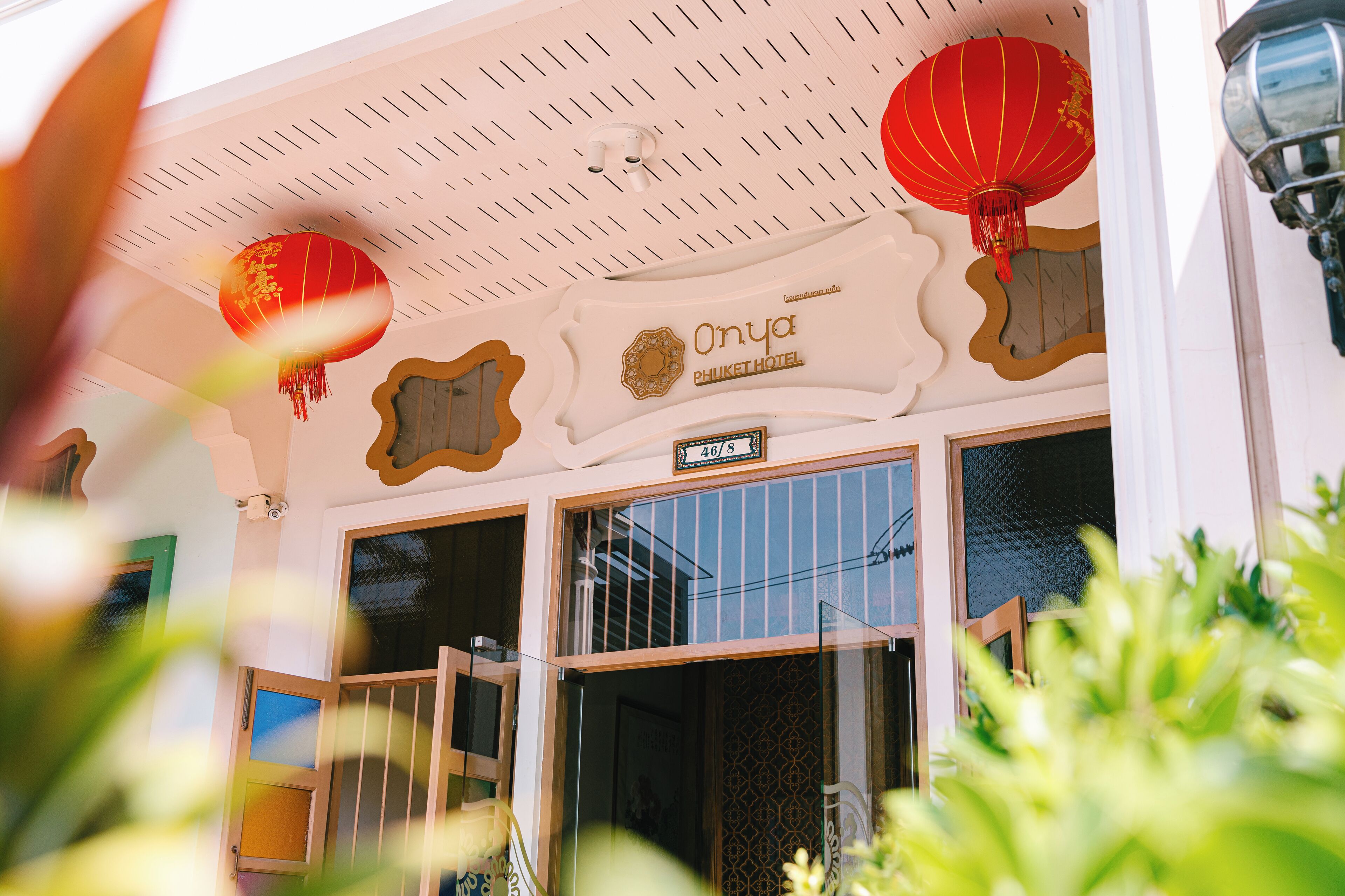 The exterior of Onya Phuket Hotel with a signboard, traditional red lanterns, and a clear view of the entrance.