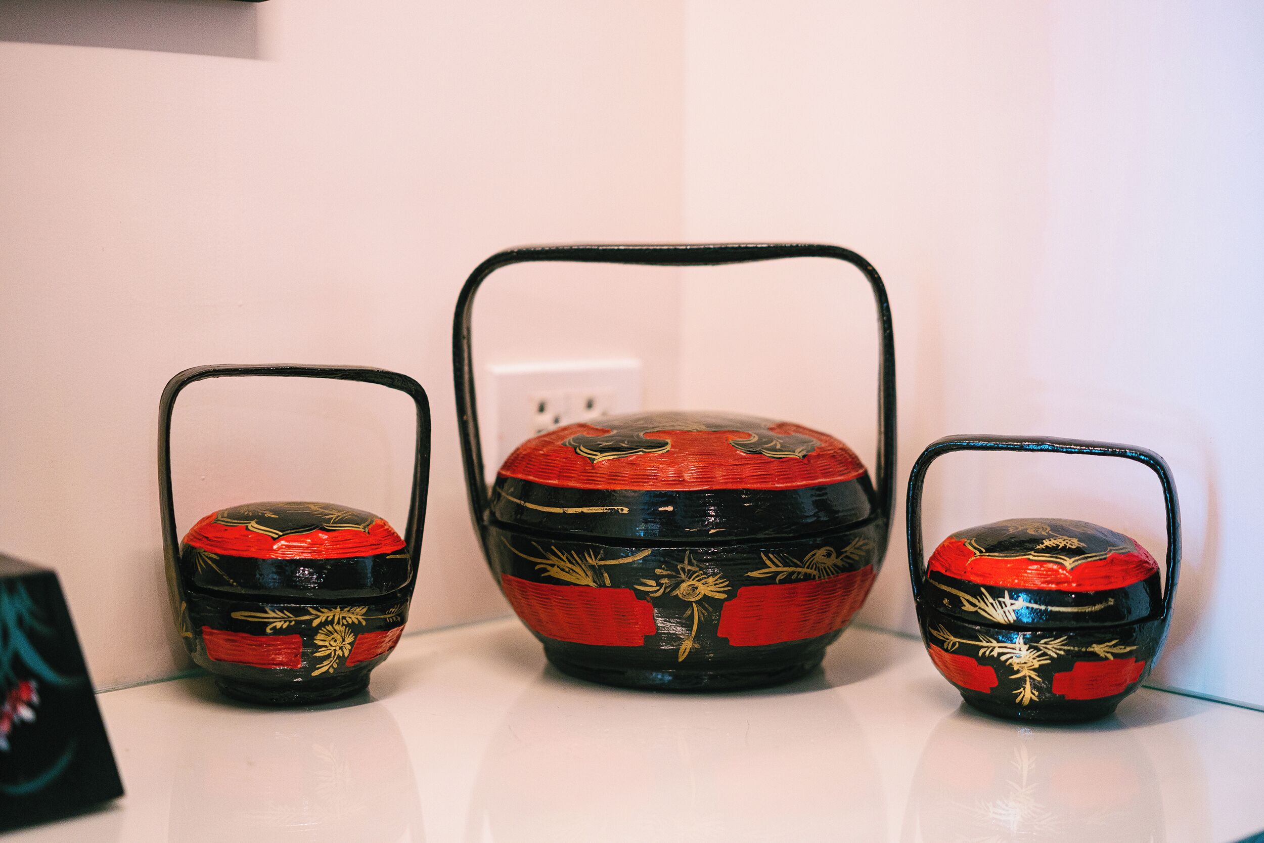 Three decorative containers with handles, one larger than the other two, on a white surface.