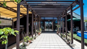 Un espacio exterior cubierto con suelo de baldosas, plantas en macetas y una piscina inflable azul.