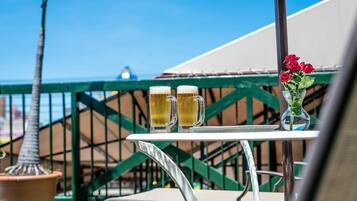 A table with two beer mugs and a vase of flowers on a balcony.