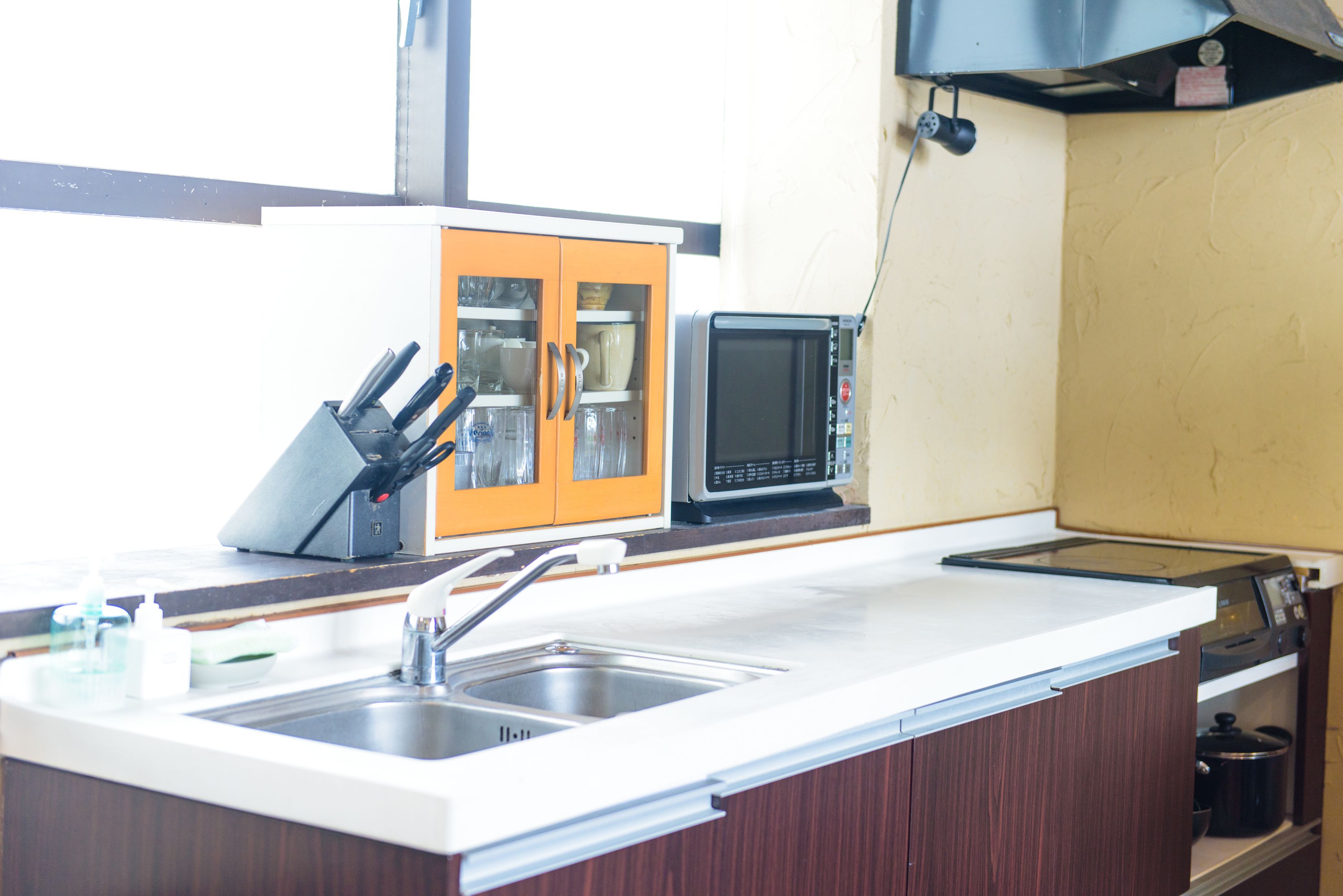 Una cocina con un lavamanos, un microondas y un armario con puertas de vidrio.