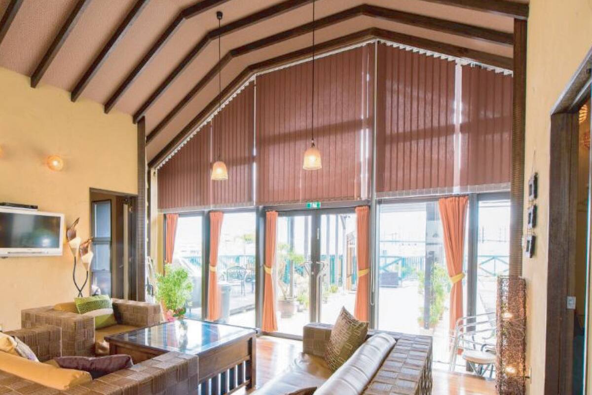 A spacious lobby with a high ceiling, large windows, and a seating area with a TV mounted on the wall.