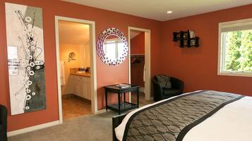 A bedroom with a bed, a chair, a desk, a mirror, and a closet.