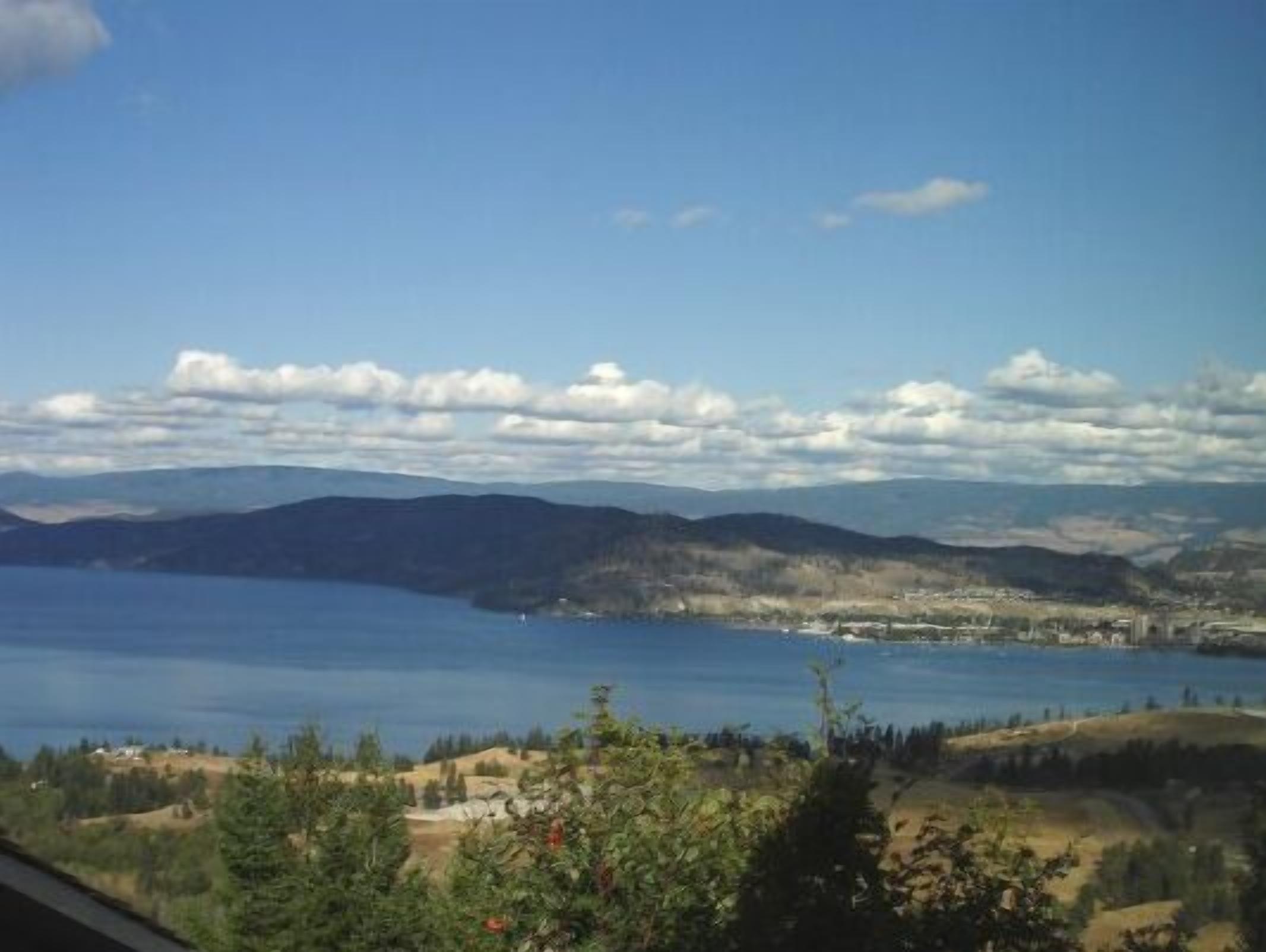 A panoramic view of a lake surrounded by hills and a clear sky.