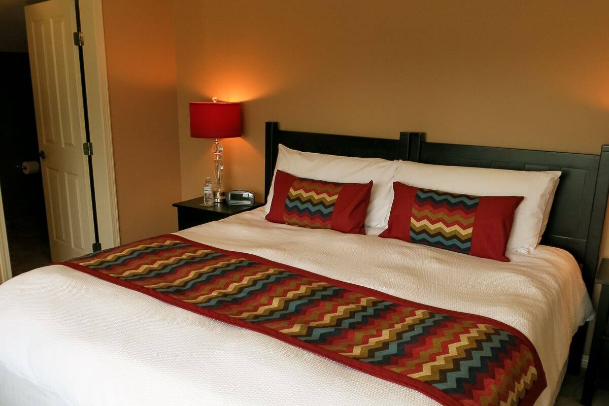 A hotel room with a large bed, a nightstand with a lamp, and a door to the left.