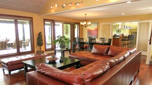 A spacious living room with a leather sectional sofa, a coffee table, and a dining area in the background. - A View of the Lake Bed & Breakfast (West Kelowna)