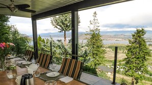 A dining area with a table set for four, overlooking a scenic view of a lake and mountains. - A View of the Lake Bed & Breakfast (West Kelowna)