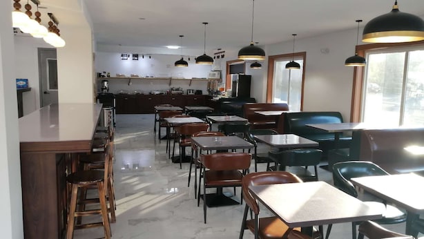 Un restaurant spacieux avec un long comptoir, ainsi que de nombreuses tables et chaises.
