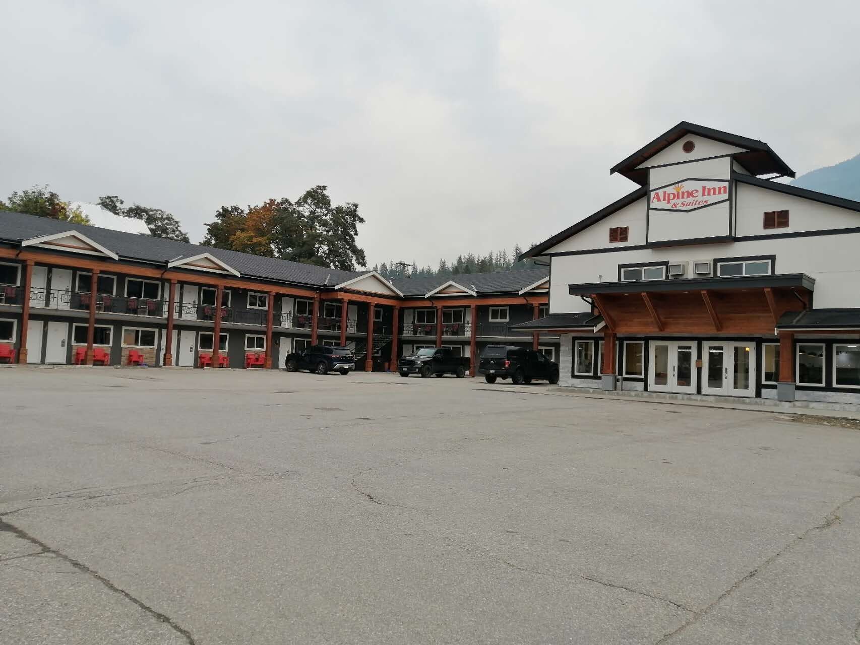 Et motel med flere værelser, en parkeringsplads og et skilt for Alpine Inn & Suites.