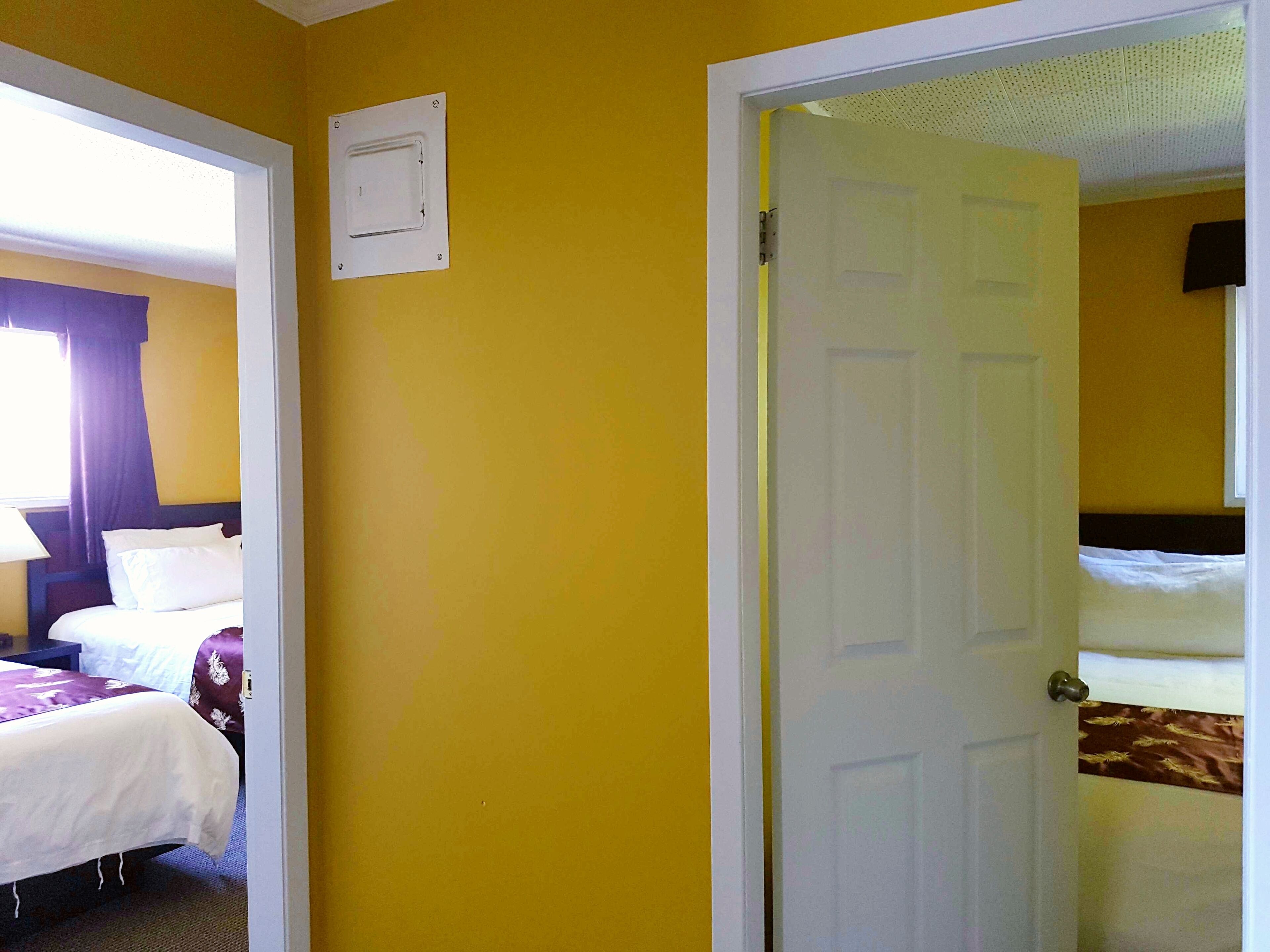 A hotel room with a bed, a bedside table, and a window with curtains.