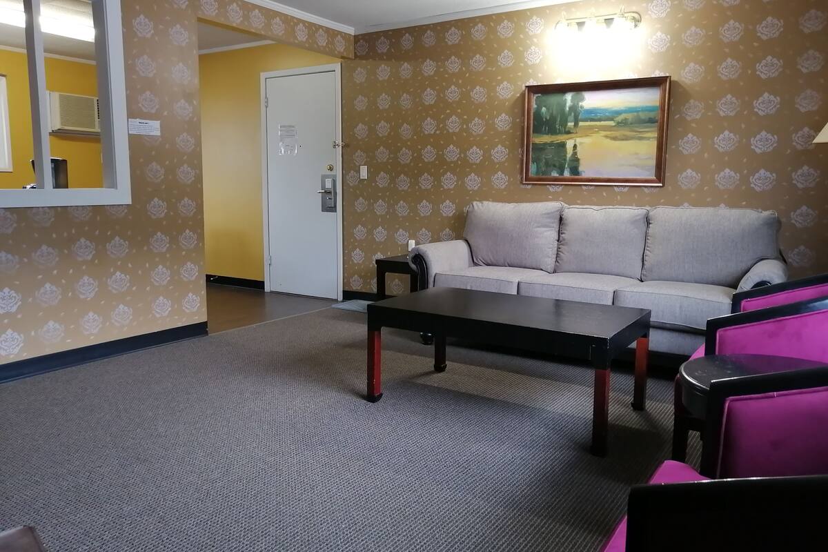 A room with a sofa, a coffee table, and a painting on the wall.