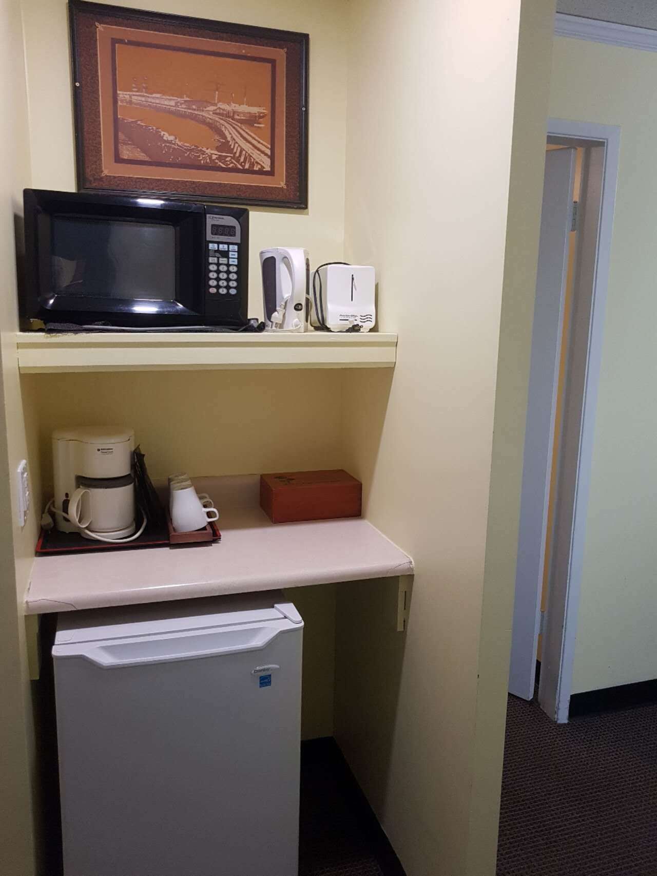 Eine kompakte Küchenzeile mit Mikrowelle, Toaster, Kaffeemaschine und einem kleinen Kühlschrank.