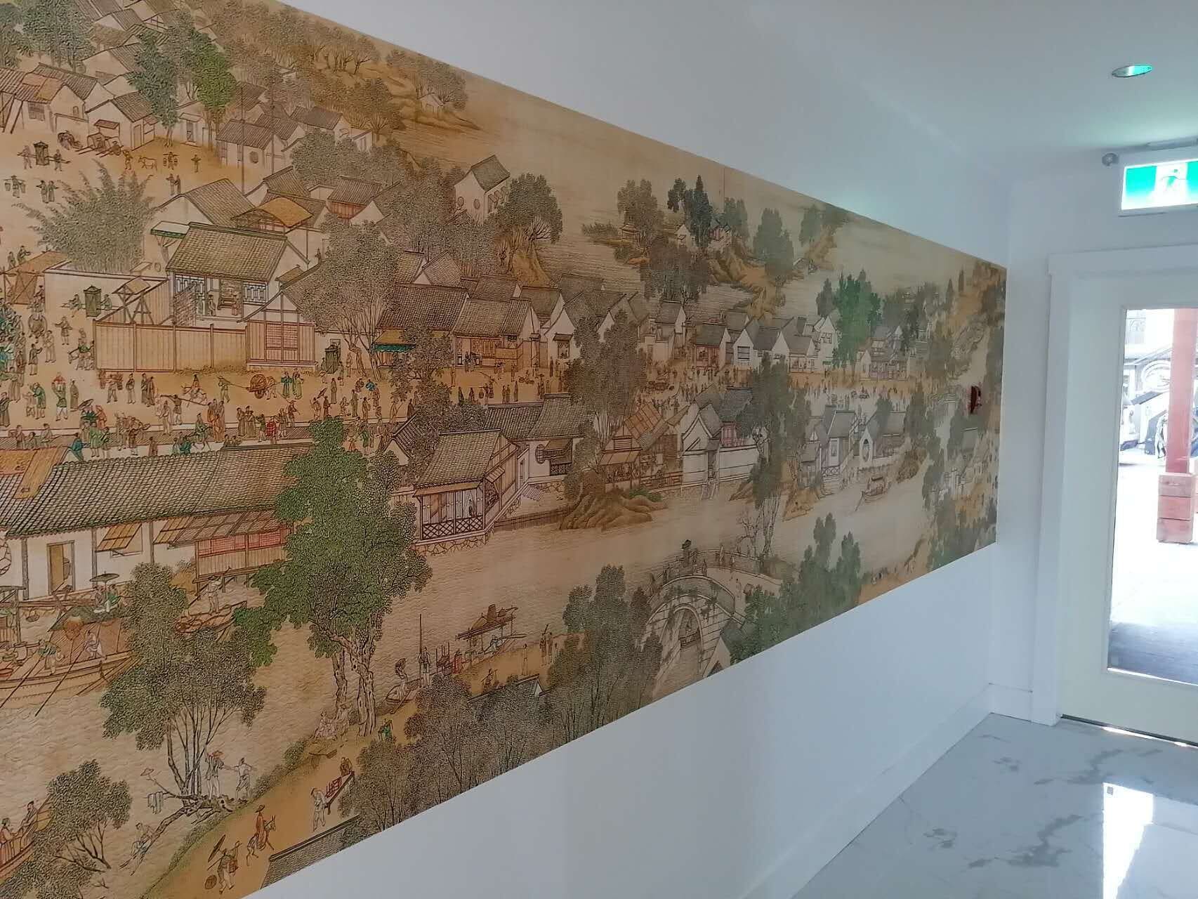 A large mural depicting a traditional village scene with buildings and people.