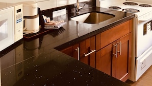 Une cuisine avec des meubles en bois, un évier en acier inoxydable, une cuisinière blanche et une machine à café.