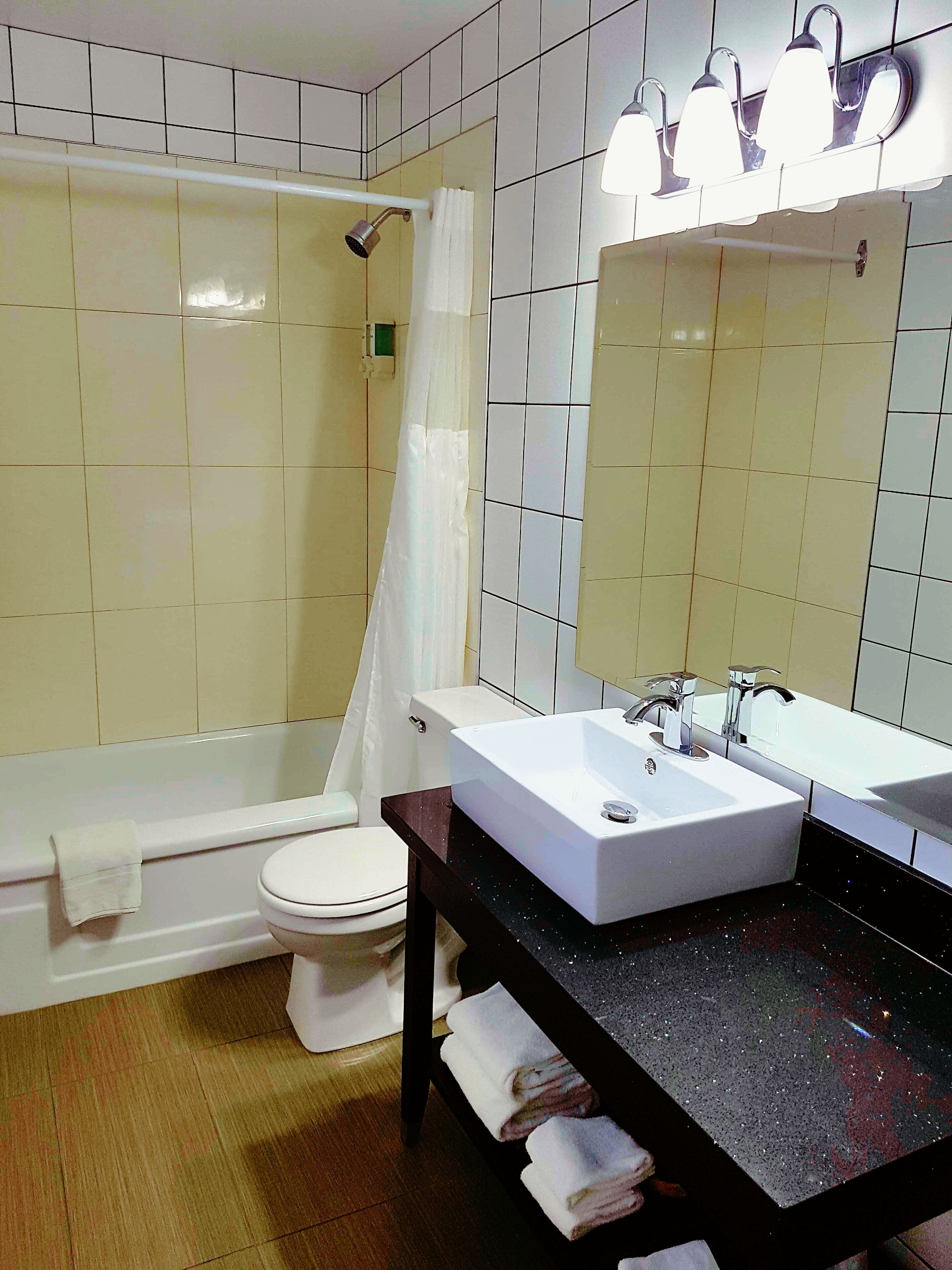 A bathroom with a bathtub, toilet, and a sink with a mirror.