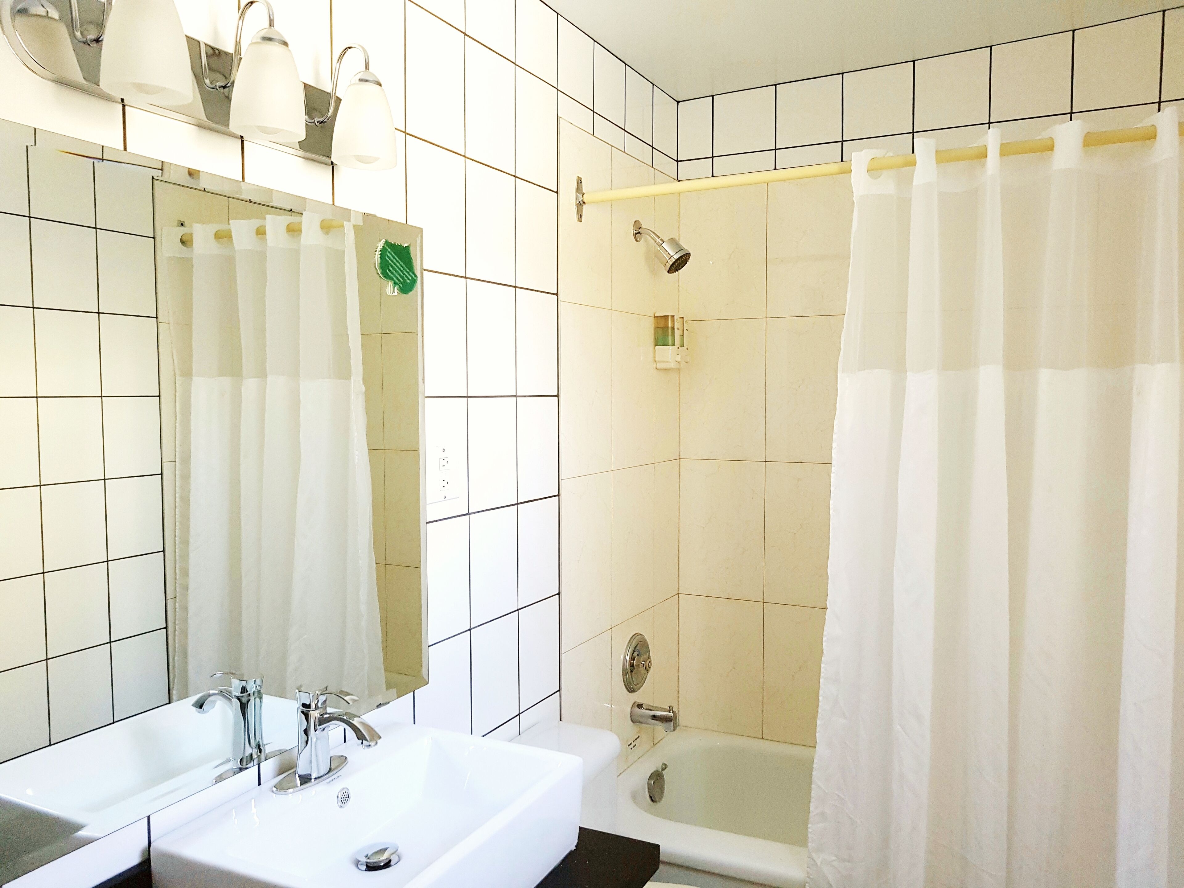 A bathroom with a sink, mirror, shower, and bathtub.