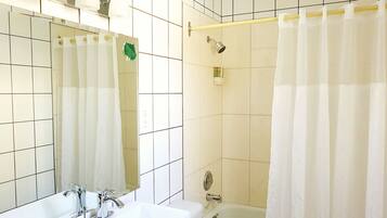 A bathroom with a sink, mirror, shower, and bathtub.