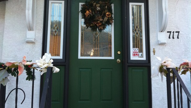 A green door with a wreath, a window with a decorative glass, and a house number 717. - Calla's Palace (Jasper)
