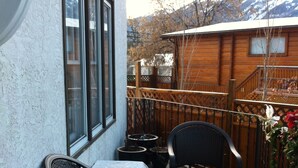 A balcony with two wicker chairs, a table, and a potted plant. - Calla's Palace (Jasper)