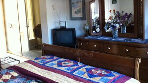 A bedroom with a bed, dresser, television, and a mirror. - Calla's Palace (Jasper)