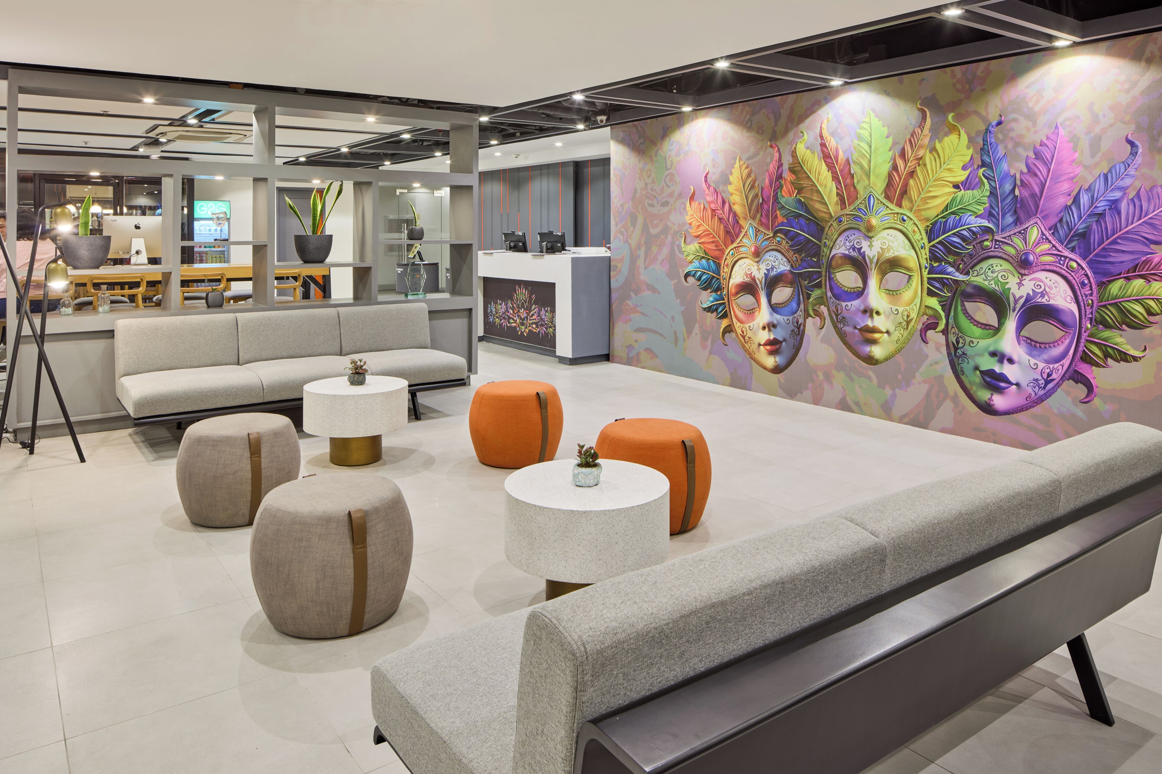 A modern lounge area with seating, a reception desk, and a colorful mural.