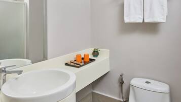 Un baño con lavamanos blanco, un espejo, un inodoro y un toallero con dos toallas.