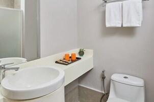 Un baño con lavamanos blanco, un espejo, un inodoro y un toallero con dos toallas.