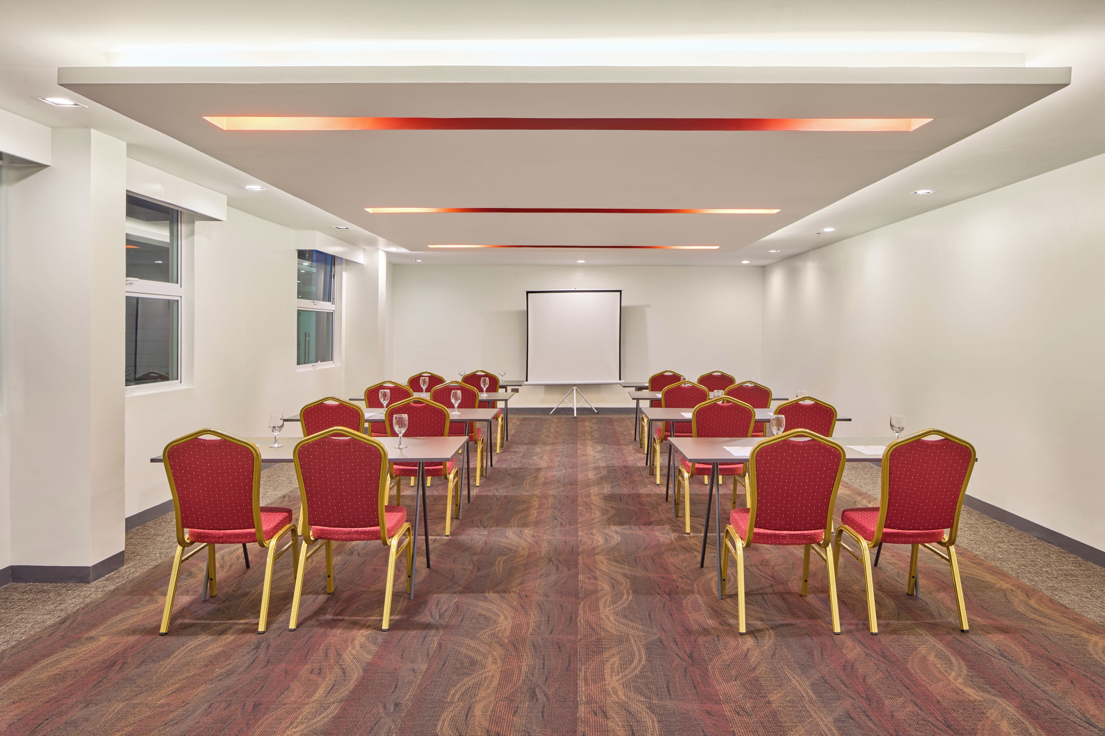 A conference room with rows of red chairs, a whiteboard, and a carpeted floor.