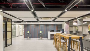 A modern office space with a long wooden table and bar stools, a reception desk, and a staircase in the background. - Go Hotels Plus Bacolod Newly Renovated (Bacolod)