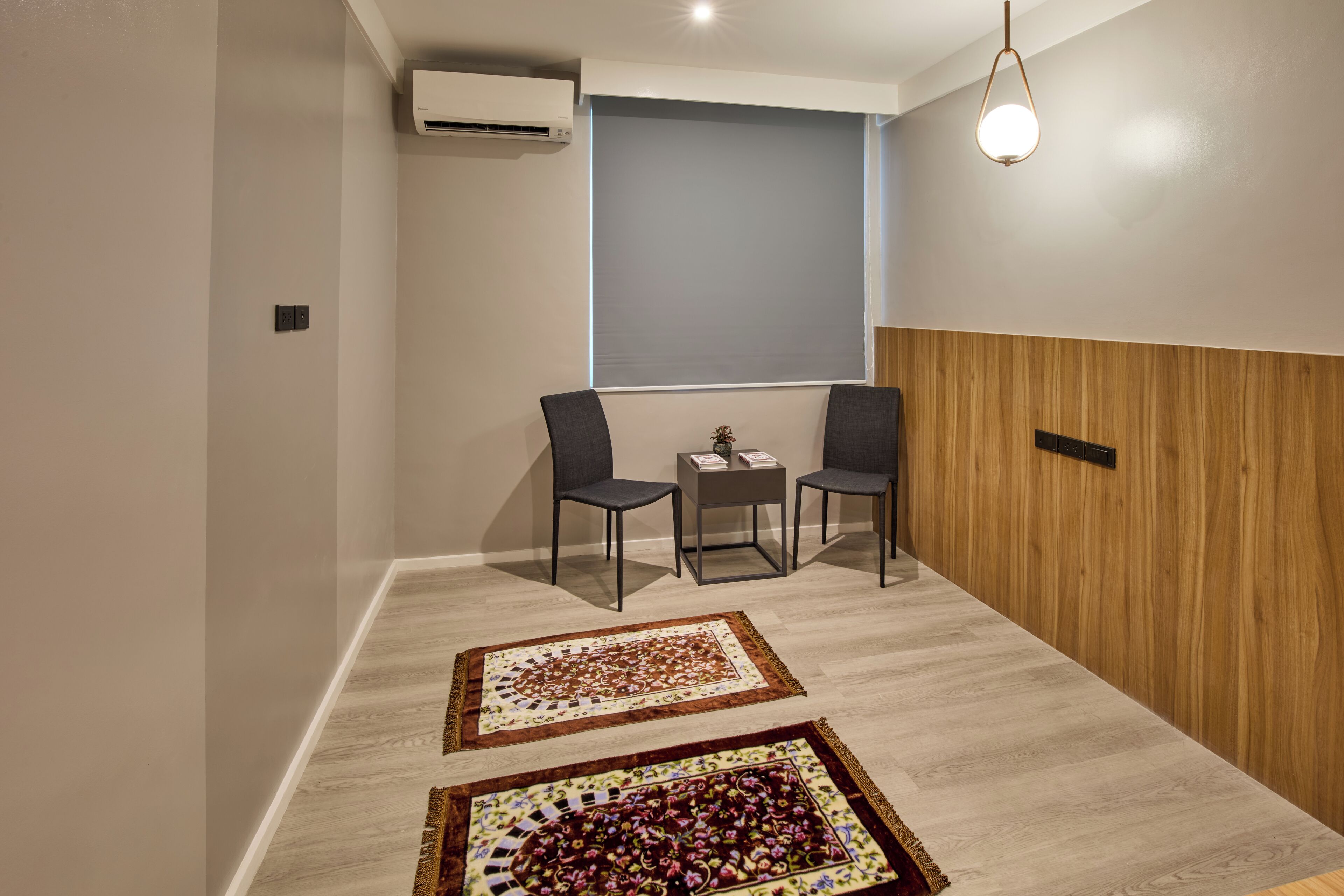 A modern room with a wooden panel wall, two chairs, a small table, and two patterned rugs.