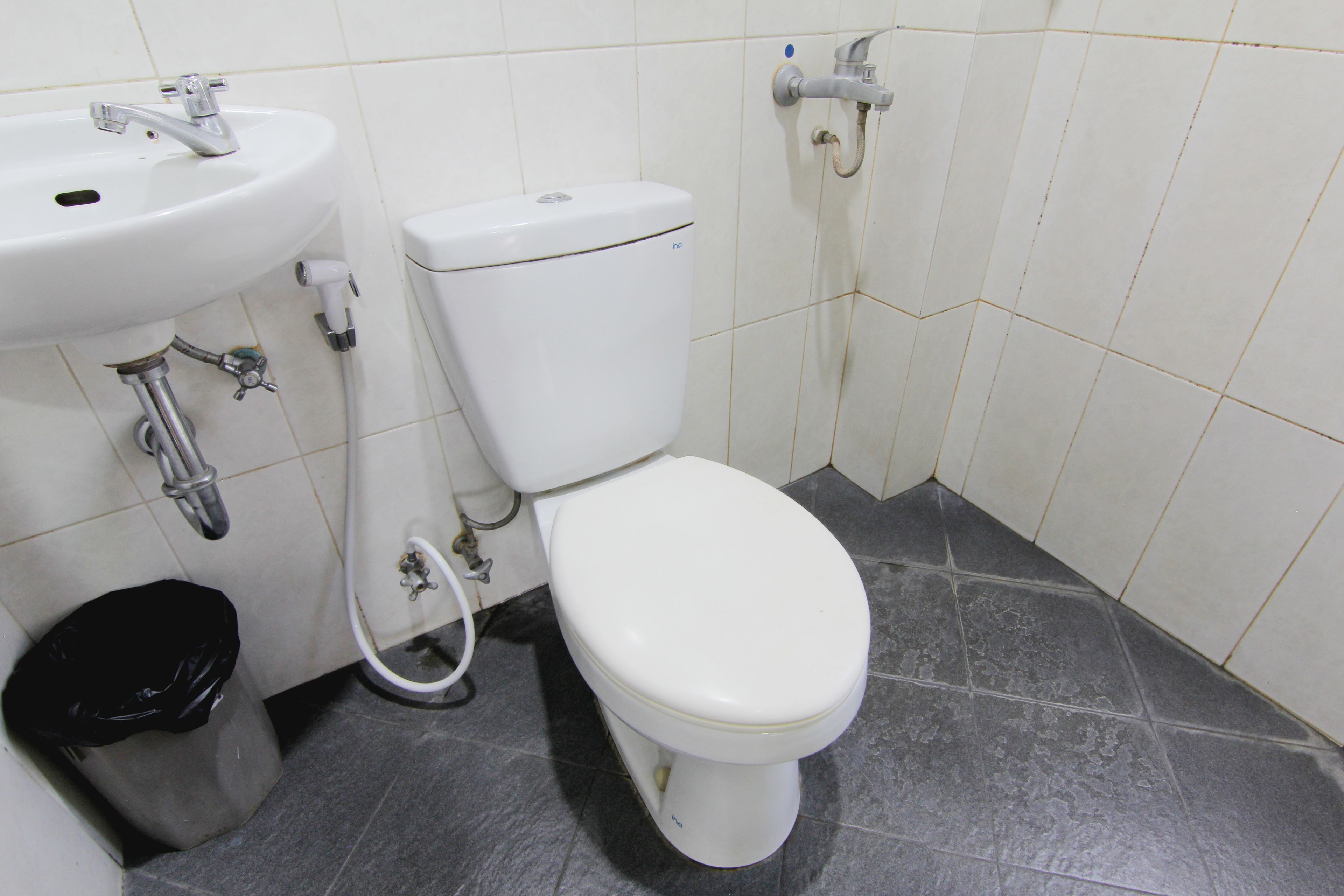 Ein Badezimmer mit einem weißen Waschbecken, einer Toilette und einer schwarzen Mülleimer.