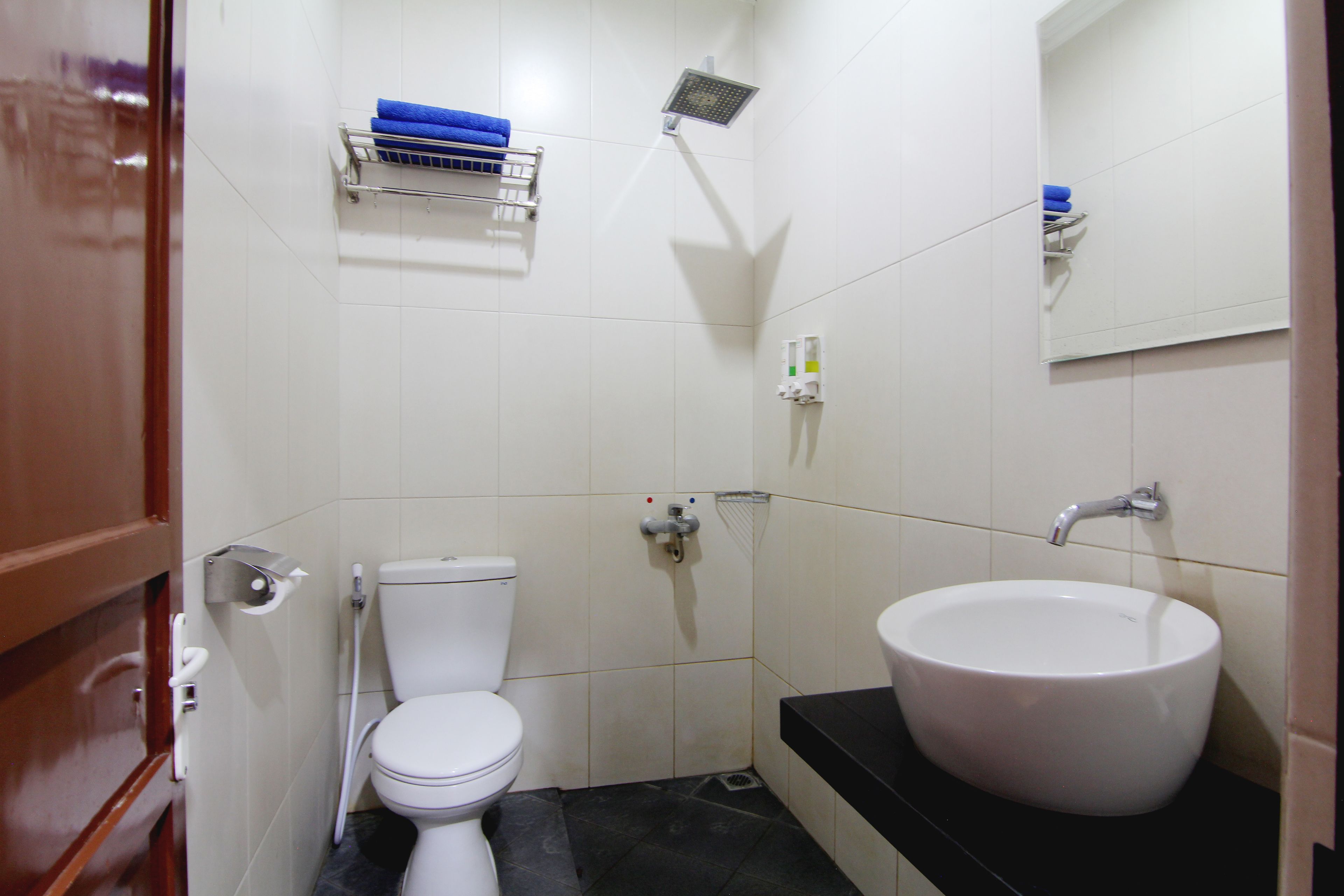 A small, clean bathroom with a white toilet, a black sink, and a shower.