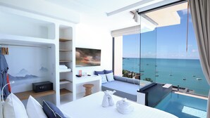 A modern hotel room with a large bed, a seating area with a view of the sea, a wardrobe, and a flat-screen TV. - Bandara Pool Villas, Phuket (Wichit)