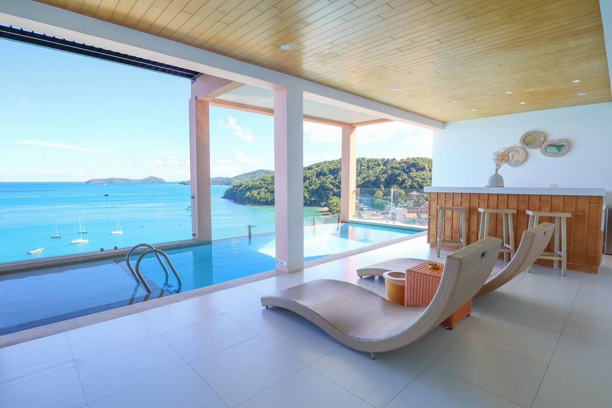 Una habitación moderna con un amplio ventanal que da a una piscina y al mar.