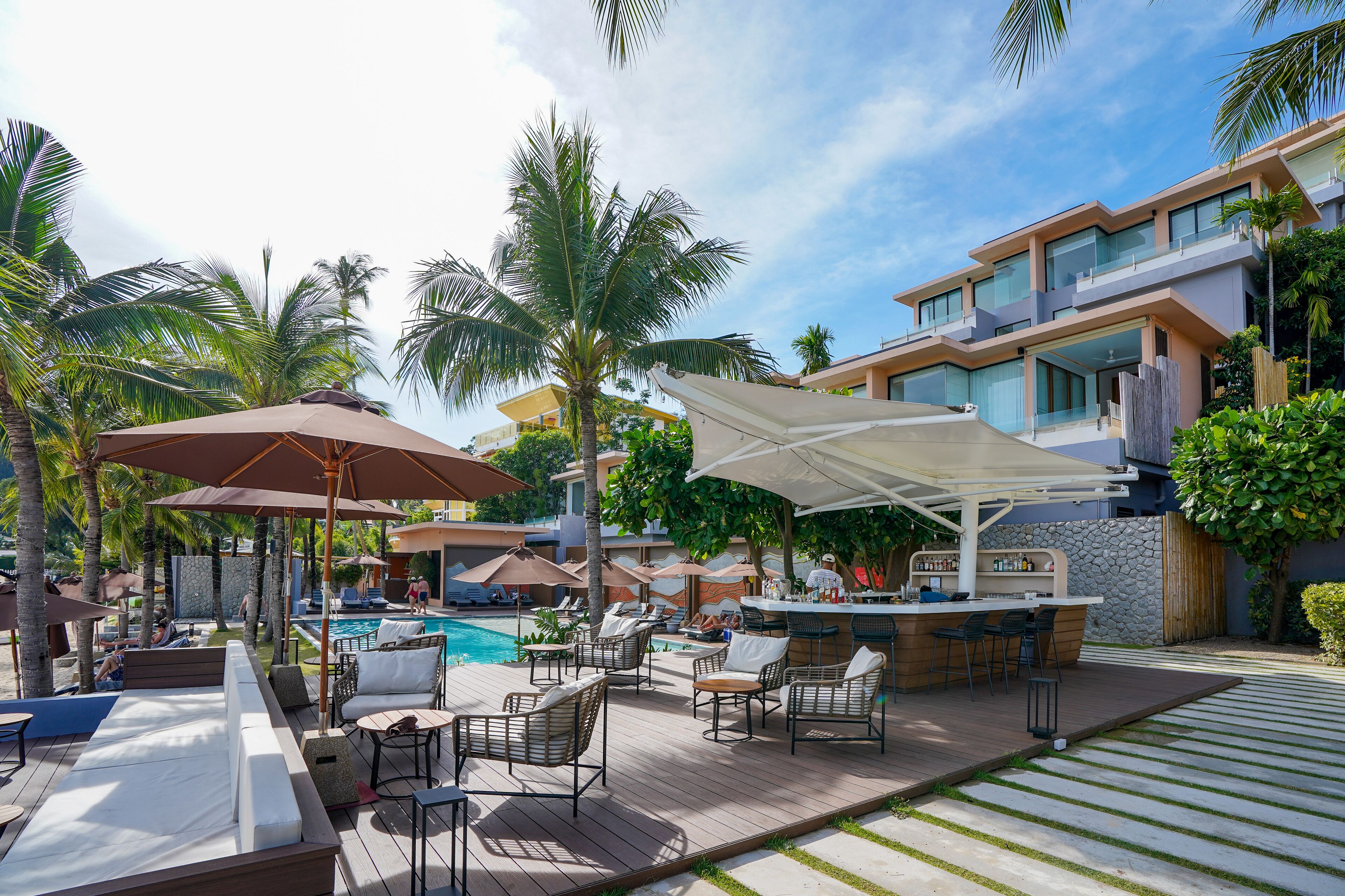 A poolside area with lounge chairs, umbrellas, and a bar.